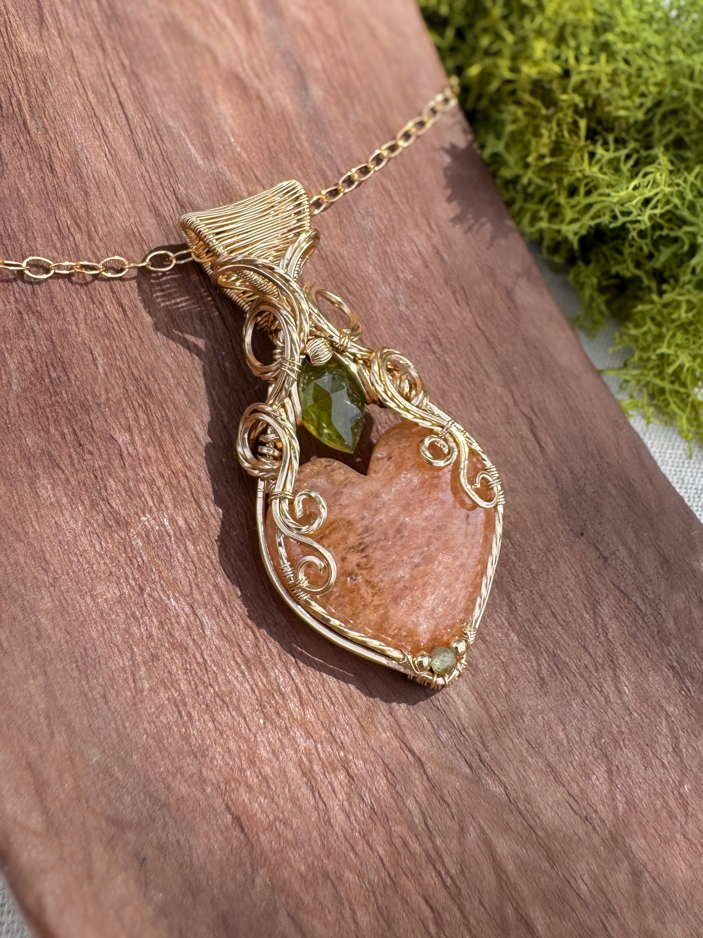 Gold pendant with green gemstone on a wooden surface
