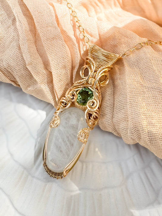 Gold necklace with a green gemstone on a beige fabric background