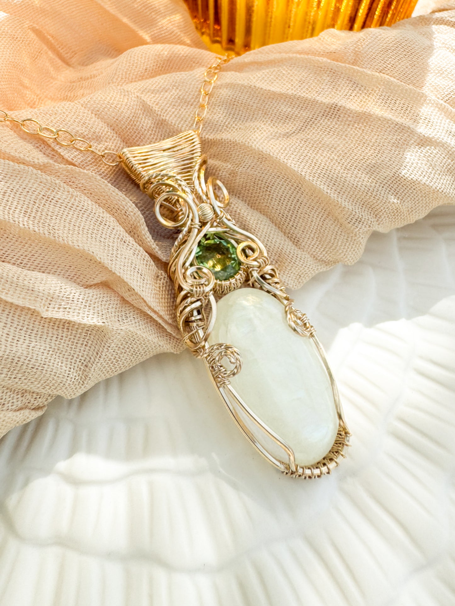 Jewelry with a green gemstone and white stone on a beige fabric background